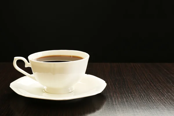 Cup of coffee on wooden table, on dark background — Stock Photo, Image