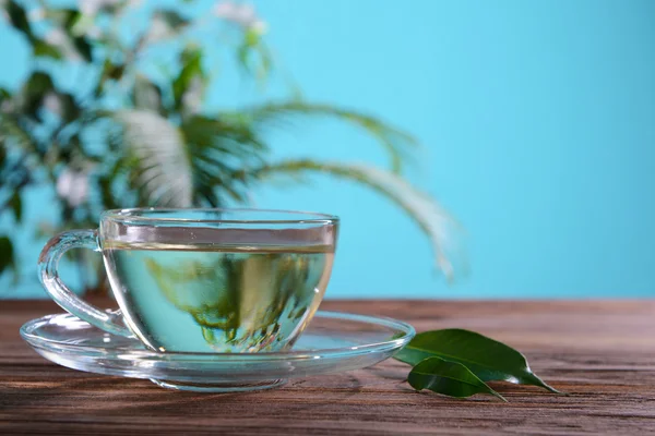 Taza de té verde en la mesa sobre fondo verde —  Fotos de Stock