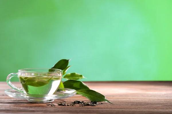 Tazza di tè verde sul tavolo su sfondo verde — Foto Stock