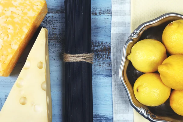 Sýr, černé špagety a citrony na dřevěný stůl horní pohled — Stock fotografie