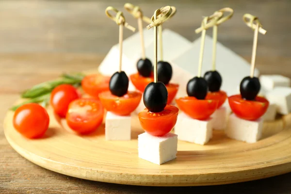 Canapés de queso con tomates cherry y aceitunas en bandeja de madera de cerca —  Fotos de Stock