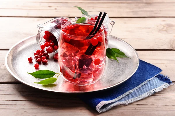 Compote with red currant in glassware on metal tray on wooden table, closeup — Stock Photo, Image