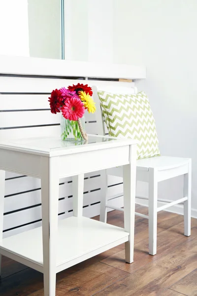 Modern interior with white chair and pillow near coffee table with colorful gerbera — Stock Photo, Image