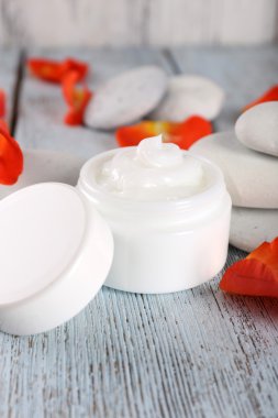 Gül yaprakları ve spa taşlar ahşap arka plan üzerinde kozmetik krem