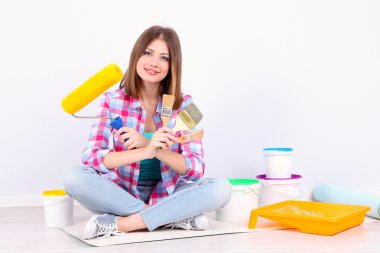 Güzel kız boyama duvar için ekipman ile katta oturan