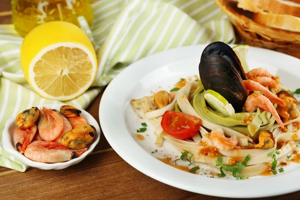 Tasty pasta with shrimps, mussels, tomatoes on plate on wooden background — Stock Photo, Image