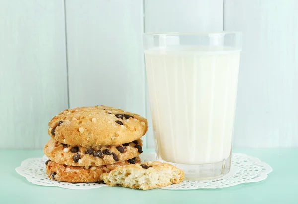 Chutné cookies a sklenici mléka na barevné dřevěné pozadí — Stock fotografie