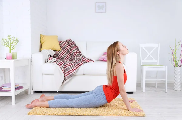 Mujer joven haciendo yoga en casa — Foto de Stock