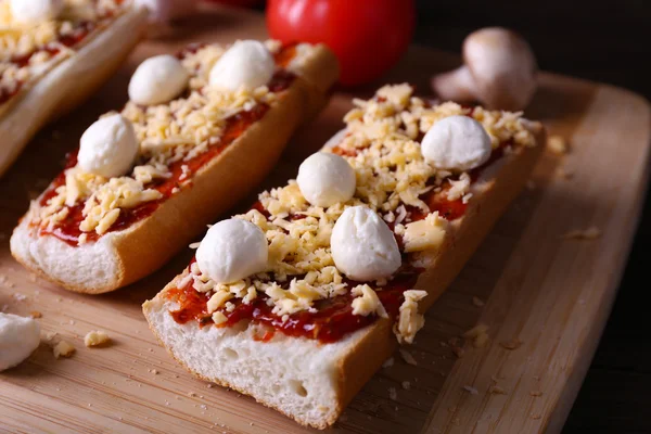 Sanduíches diferentes com legumes e queijo na tábua de corte na mesa de perto — Fotografia de Stock