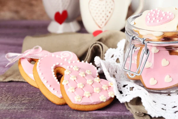 Cookies em forma de coração para dia dos namorados, bule e xícaras sobre fundo de madeira cor — Fotografia de Stock