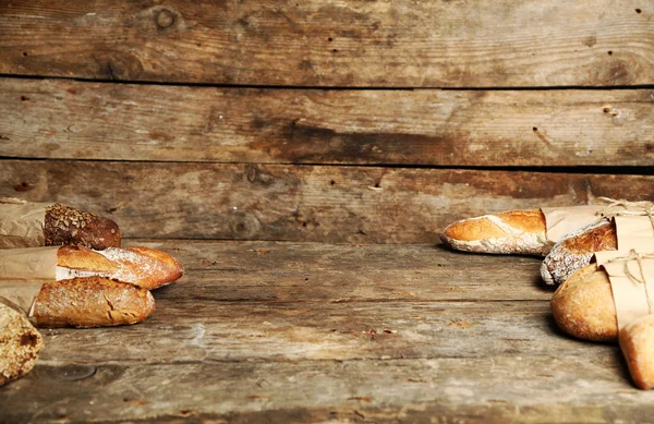 Verschillende vers brood, op oude houten tafel — Stockfoto