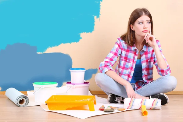 Menina bonita sentada no chão com equipamento para pintura de parede — Fotografia de Stock