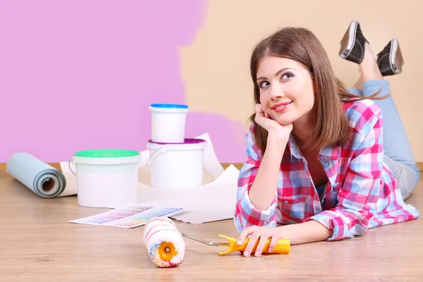 Beautiful girl lying on floor with equipment for painting wall — Stock Photo, Image