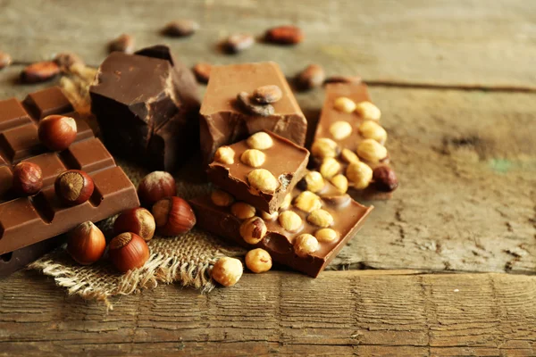 Bodegón con conjunto de chocolate con nueces en la mesa de madera, primer plano —  Fotos de Stock