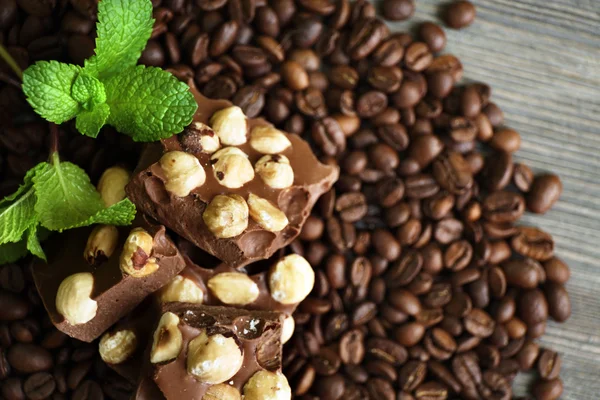 Chocolade met munt en koffie bonen op houten tafel, close-up — Stockfoto