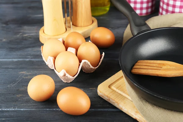 Stilleben med ägg och pan på trä bakgrund — Stockfoto