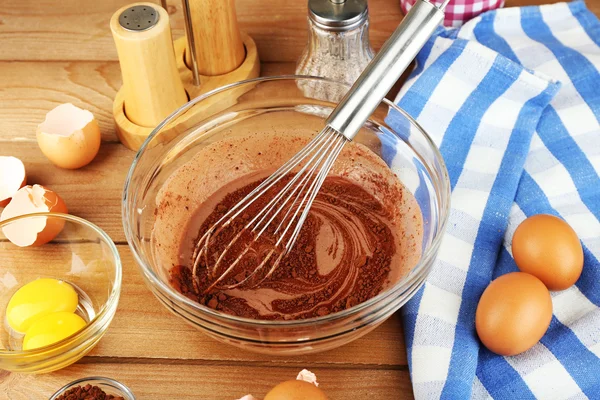 Préparation crème aux œufs et cacao dans un bol en verre sur fond en bois — Photo