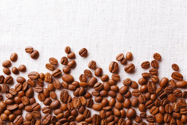 Frame of coffee beans on color sackcloth background — Stock Photo, Image