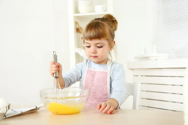 Pieni tyttö valmistaa evästeitä keittiössä kotona — kuvapankkivalokuva