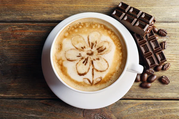 Copa de arte café con leche con granos y chocolate en la mesa de madera, vista superior — Foto de Stock