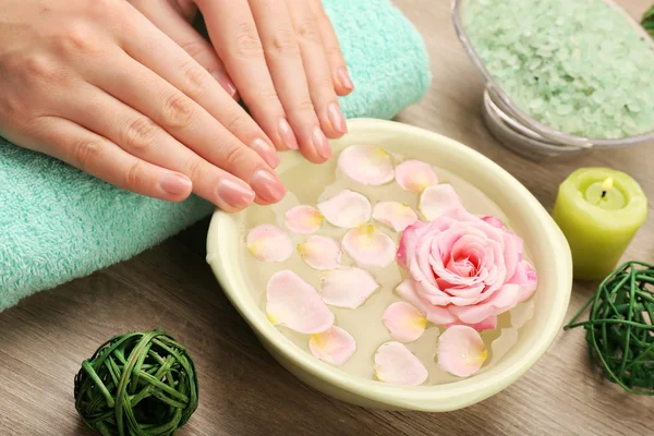 Female hands and bowl of spa water with flowers, closeup — Stock Photo, Image
