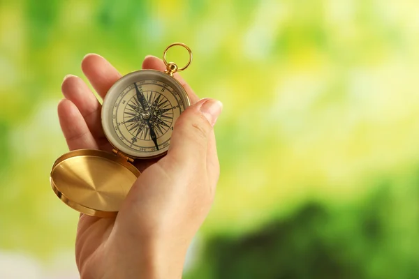 Vrouwelijke hand met kompas op heldere onscherpe achtergrond — Stockfoto