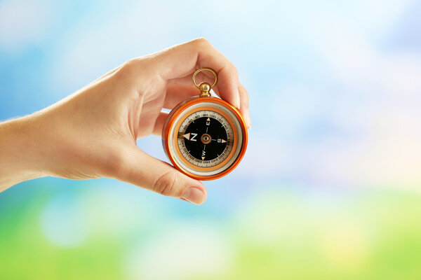 Female hand with compass on bright blurred background