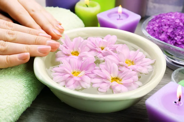 Mãos femininas com tigela de água de spa de aroma em mesa de madeira, close-up — Fotografia de Stock