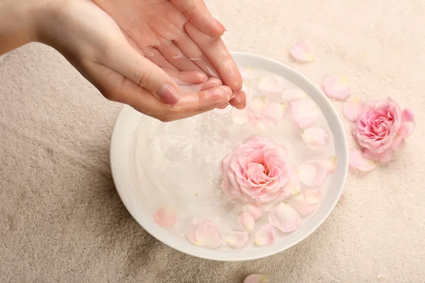 Manos femeninas con tazón de agua de spa aroma en la mesa, primer plano — Foto de Stock