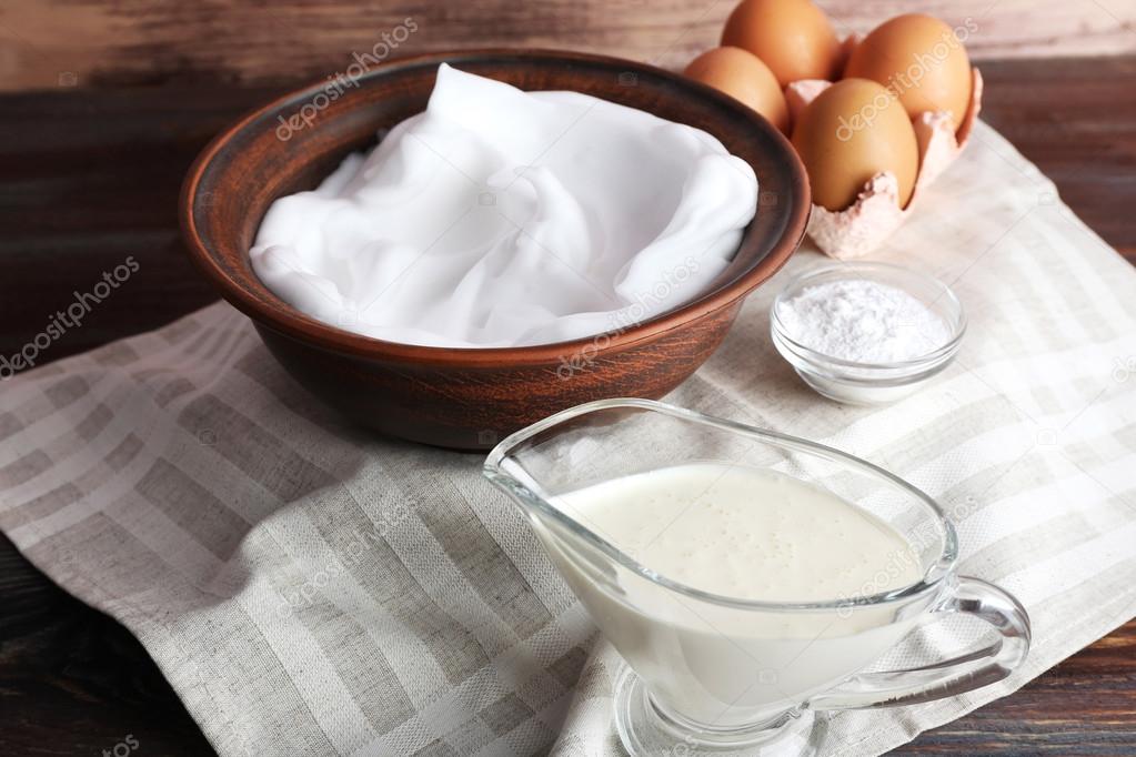 Whipped egg whites and other ingredients for cream on wooden table, closeup