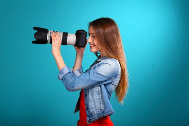 Mavi arka plan üzerinde çekim genç kadın fotoğrafçı