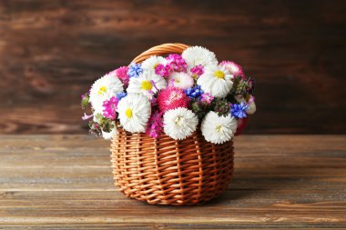 Hasır sepet ahşap arka plan üzerinde güzel renkli papatya