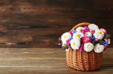 Hasır sepet ahşap arka plan üzerinde güzel renkli papatya