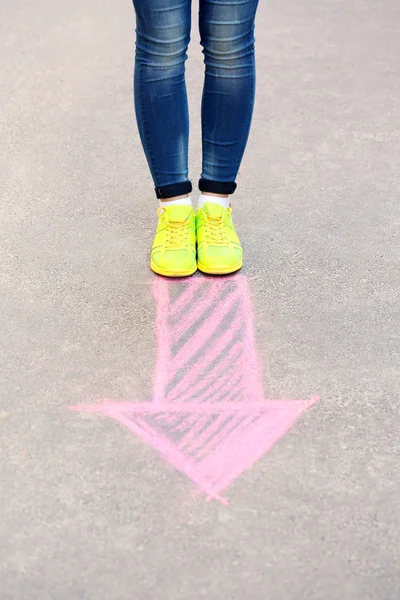 Female feet and drawing arrow on pavement background — Stock Photo, Image