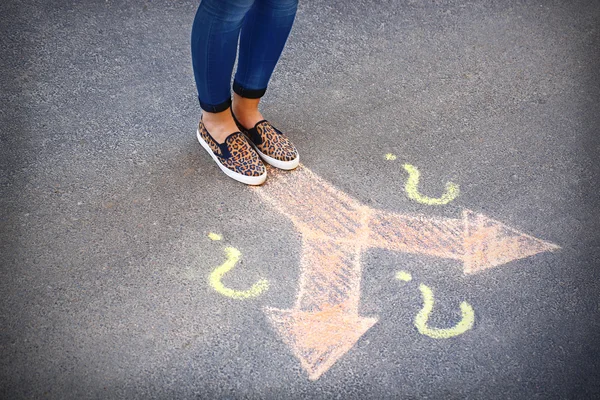 Pies femeninos y flechas de dibujo sobre el fondo del pavimento — Foto de Stock