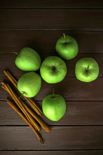 Pommes vertes avec bâtonnets de cannelle sur fond en bois — Photo