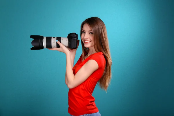 Młoda kobieta fotograf robienia zdjęć na niebieskim tle — Zdjęcie stockowe