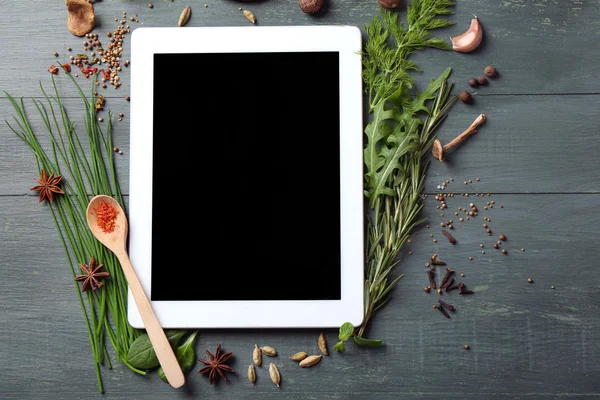 Tableta digital con hierbas frescas y especias sobre fondo de madera — Foto de Stock