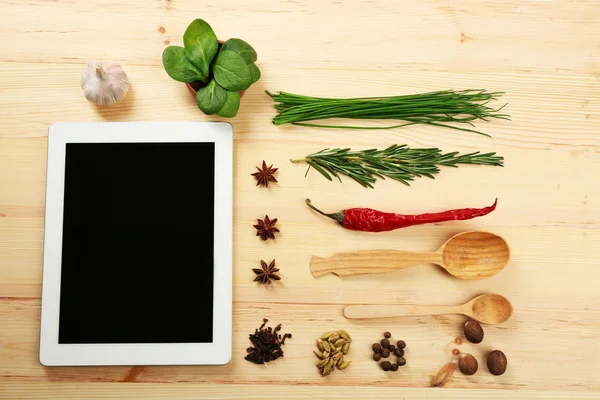 数字平板与新鲜的药草和香料木制背景 — 图库照片