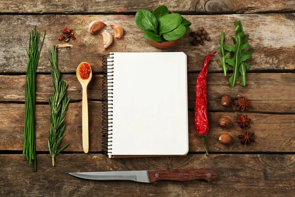 Livro de receitas aberto com ervas frescas e especiarias em fundo de madeira — Fotografia de Stock