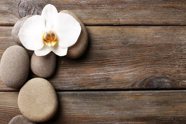 Spa stones and orchid flower on wooden background — Stock Photo, Image