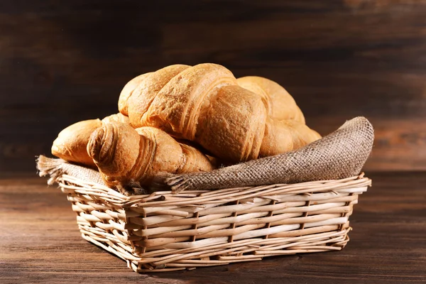 Läckra croissanter i rotting korg på tabell närbild — Stockfoto
