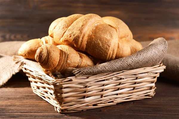 Delicious croissants in wicker basket on table close-up — Stock Photo, Image