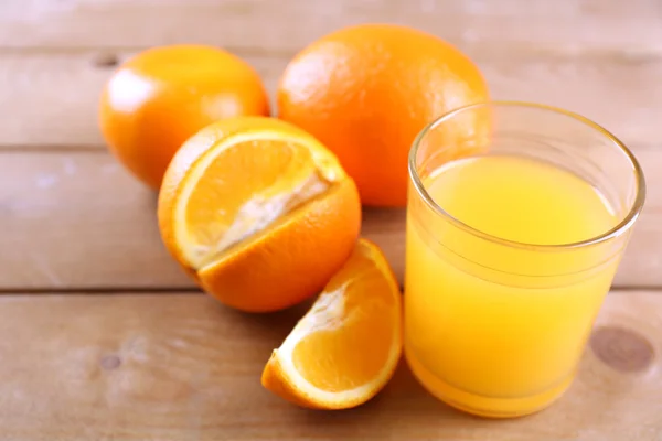 Copo de suco de laranja e fatias em fundo de mesa de madeira — Fotografia de Stock