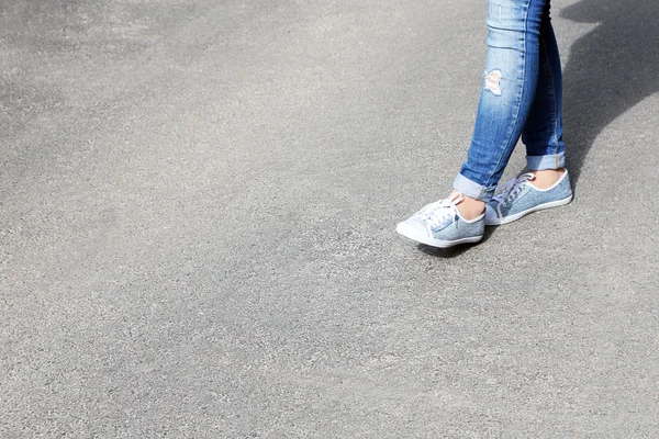 Ženské nohy nad šedá asfaltová pozadí — Stock fotografie