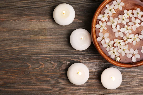 Wellness-Stillleben mit Blütenblättern und Kerzenschein auf Holzgrund — Stockfoto