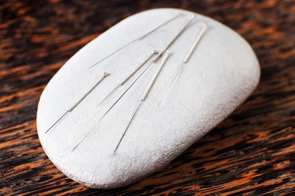 Acupuncture needles on wooden plate with spa stone, closeup — Stock Photo, Image