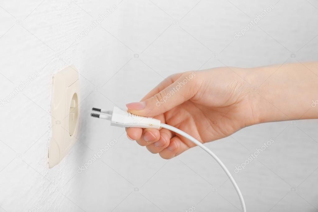 Hand putting plug in electricity socket close up Stock Photo by