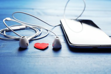 Hareket eden telefon ve kulaklık renk ahşap arka plan üzerinde