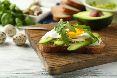Yumurta, avokado ve roka ahşap arka plan üzerinde lezzetli sandviç